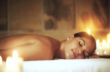 Woman, relax and spa treatment on massage bed for glow, wellness and cosmetics with candles. Zen,...