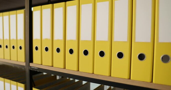 Yellow organized folders structure with materials on shelf of rack in company premise. Concept of saving data in office building archive storage slow motion