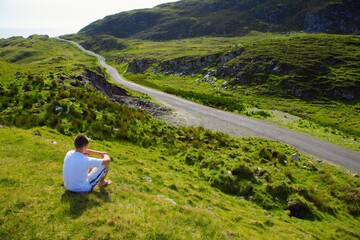Fototapeta premium Man Sitting Beside Road