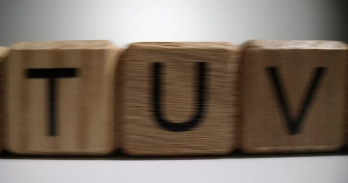 Wooden cubes with English alphabet put in long row on white table. Educational blocks designed for kids games and development on grey background