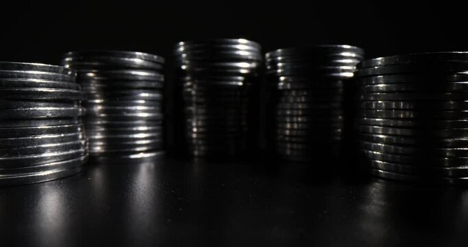 Stacks of silver coins standing in long curvy row reflecting on dark table. Money investments and accumulation concept. Financial savings