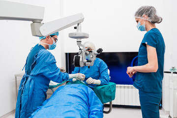 Skilled female surgeon and his medical team performs precise eye surgery on an elderly patient, restoring vision with latest medical technology and cutting-edge techniques. Modern eye surgery concept.