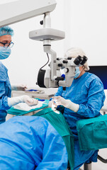 Skilled female surgeon and his medical team performs precise eye surgery on an elderly patient,...