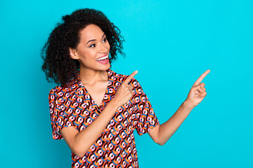 Photo of girlish excited lady dressed print shirt pointing finger looking empty space isolated teal...