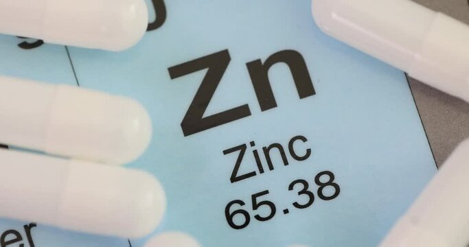 White capsules of zinc lying on blue cardboard with information. Useful vitamin supplement for improving human health and body condition