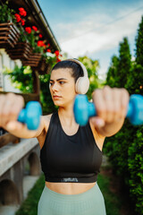 One young caucasian woman is doing exercises with dumbbells	
