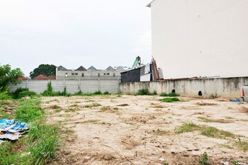 A vacant lot with a fence and a building in the background. The lot is empty and has no people or...