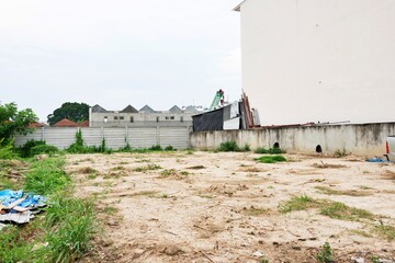 A vacant lot with a fence and a building in the background. The lot is empty and has no people or vehicles,land for sale