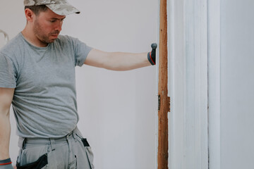 A young man dismantles old skirting boards.