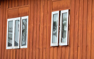 The wooden house has two windows, one of which is open