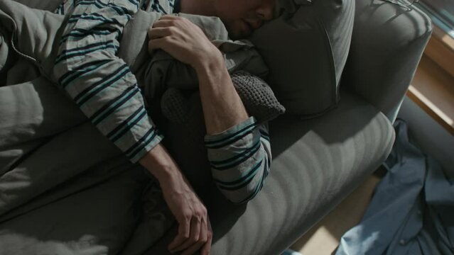 A tired and depressed middle-aged man wakes up on the sofa in his flat