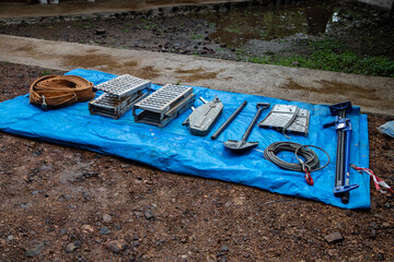 Recovery equipment for unstacking 4x4 vehicle out of muddy road, sand plates, mechanical winch, pooling ropes, high lift jack, shovel. People using protective gear, team work and efforts
