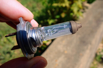 Functional, used halogen car bulb held in hand.