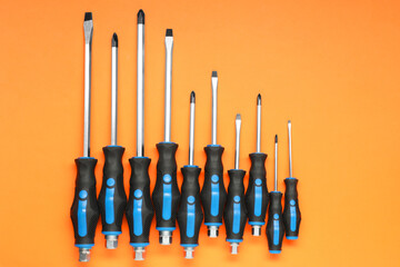 Set of screwdrivers on orange background, flat lay