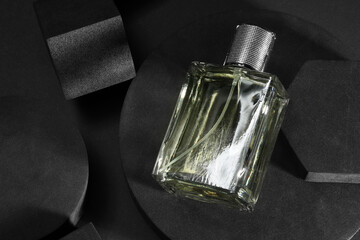 Stylish presentation of luxury men`s perfume in bottle on black background, top view. Space for text