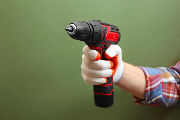 Handyman holding electric screwdriver on pale green background, closeup