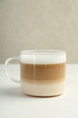 Aromatic coffee in glass cup on white wooden table