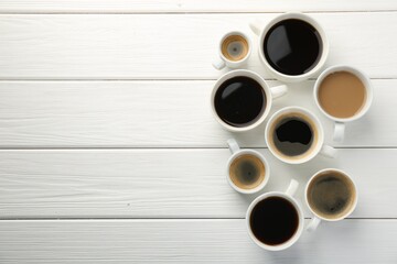 Different coffee drinks in cups on white wooden table, flat lay. Space for text