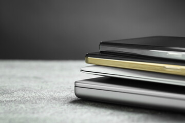 Stack of electronic devices on grey table, closeup. Space for text