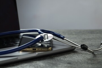 Modern electronic devices and stethoscope on grey table. Space for text