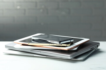 Stack of electronic devices on white table, closeup. Space for text