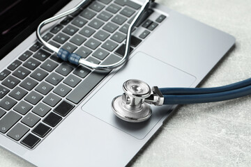 Stethoscope and modern laptop on grey table, closeup