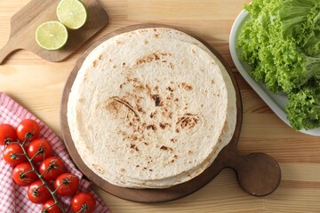 Many tasty homemade tortillas and products on wooden table, flat lay