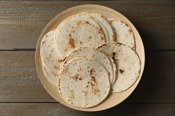 Many tasty homemade tortillas on wooden table, top view