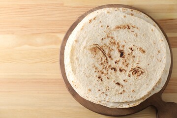 Many tasty homemade tortillas on wooden table, top view. Space for text