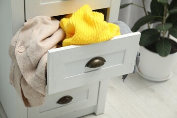 Cluttered chest of drawers indoors. Clothes in mess