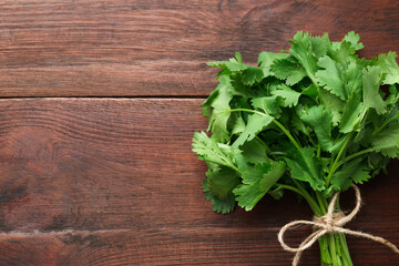 Bunch of fresh coriander on wooden table, top view. Space for text