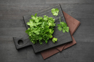 Bunch of fresh coriander on black wooden table, top view