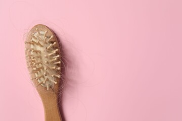 Wooden brush with lost hair on pink background, top view. Space for text