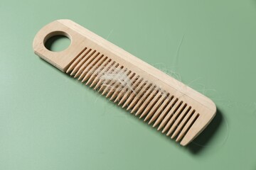 Wooden comb with lost hair on green background