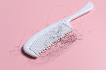 Comb with lost hair on pink background