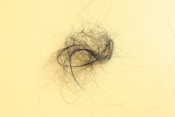 Pile of lost hair on yellow background, top view