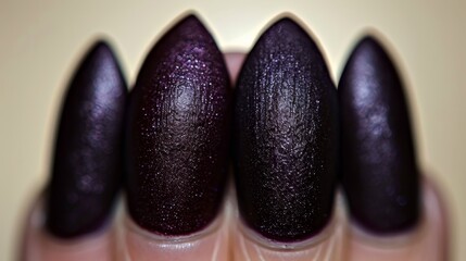  A tight shot of a hand with dark purple nail polish at the fingertip