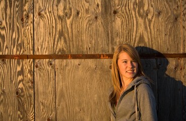 Young Woman Stands Against Old Wooden Building