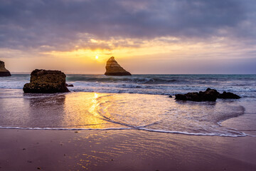 Sunrise at Praia Dona Ana beach, with its spectacular sea stacks and cliffs in Lagos, Algarve,...