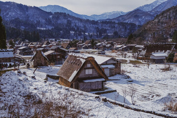 Shirakawa-go in winter, snow falling over the ground, house, historic village in valley, Japan.