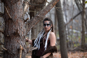 Outdoor portraits of a female viking in a forest setting. She is wearing a fur coat and full...