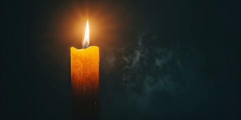 A single candle burning in darkness with negative space
