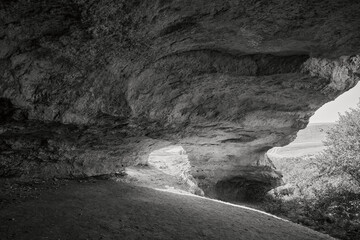 Exploring the mystical depths a black and white photo of a cave with light streaming in