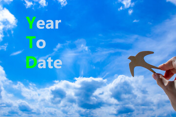 YTD year to date symbol. Concept words YTD year to date on beautiful blue sky clouds background....