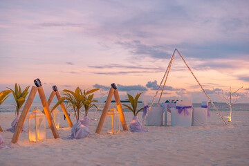 Amazing romantic dinner table on sandy beach floral decor candles under sunset sky. Romance love,...