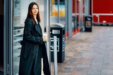 young girl with a glass of coffee in the morning in the city