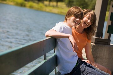 Teenagers Sitting On A Bench By Water