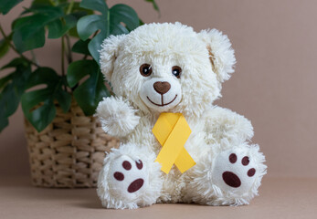 Toy bear with a yellow ribbon on a nude background.