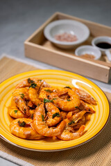 still life, shrimps on a yellow plate, spices and sauce behind them