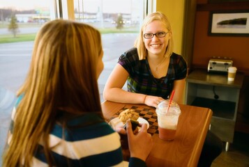 Two Women Talking At A Table In A Cafe